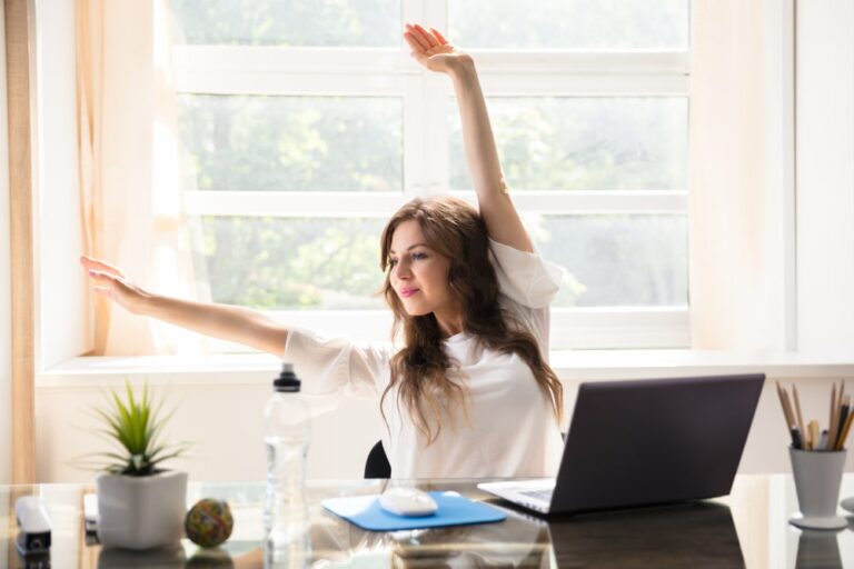 Happy, young business woman stretching her arms In office, mental health at work